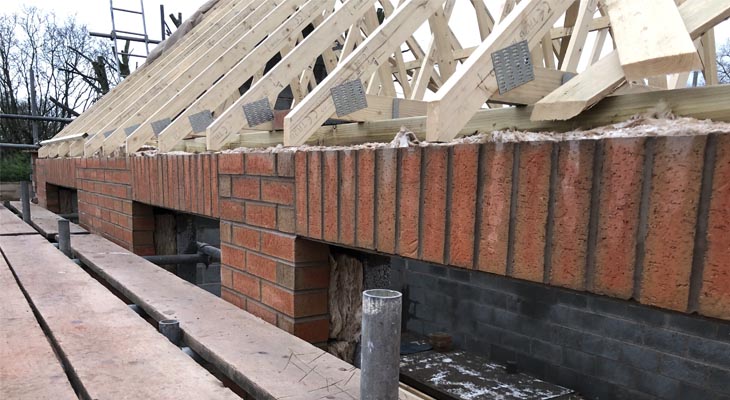 Close up of final courses of bricks up to wall plate.